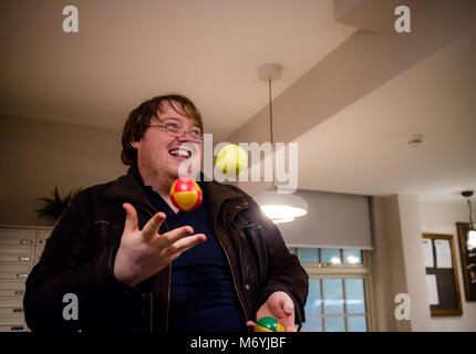 Un uomo la giocoleria in casa sua con tre sfere, presi da un angolo Foto Stock