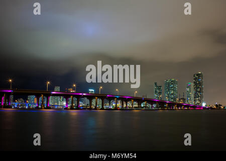 Vista della MacArthur Causeway bridge a Miami la notte sopra l'acqua. Luna nascondendo dietro le nuvole. Foto Stock