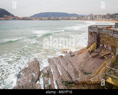 L'uomo con il suo bordo è quasi pronto per la navigazione sul flysh scogliera di La Concha Beach in San Sebastian, Paesi Baschi Foto Stock