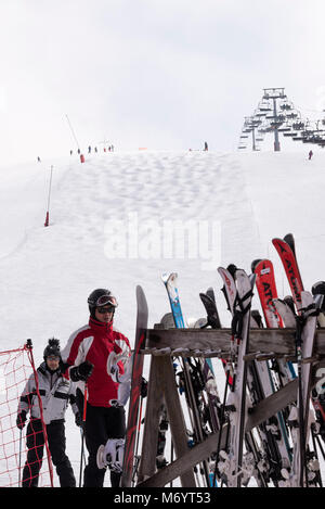 Paia di sci in un rack al fondo di una pista da sci con la seggiovia e Mogul pendio a Les Gets vicino a Morzine Haute Savoie Portes du Soleil Francia Foto Stock