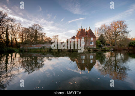 Square oast house si riflette nel fiume Beult, Yalding, Kent, Regno Unito. Foto Stock