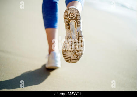 Close up della suola di una scarpa da running, corsa sulla spiaggia Foto Stock