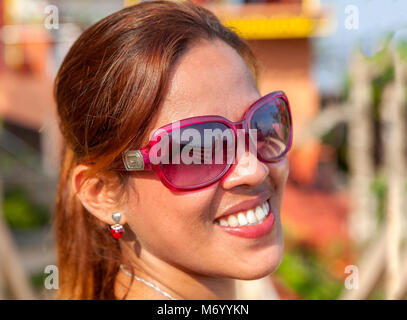 Close-up di testa e spalle il ritratto di una bella donna filippina con un grande sorriso indossando occhiali da sole nelle Filippine. Foto Stock