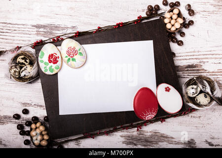 Bella pasqua vetrato gingerbread cookie e biglietto di auguri su un tavolo di legno.Le uova di cioccolato e sfere. Vista da sopra.Copia dello spazio. Foto Stock