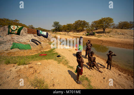 Gli abitanti del nord della Namibia a lavare i panni in un piccolo fiume vicino Ehomba nel Kaokoland, vicino all'area di confine Angola, Namibia Foto Stock