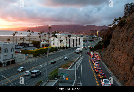 Panoramica delle vetture in California la voce della pendenza verso il basso da Santa Monica scogliere sulla Pacific Coast Highway di Los Angeles, CA al tramonto. Foto Stock