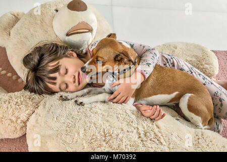 6 anno vecchia ragazza baciato dal suo cane su un gigantesco orso Foto Stock