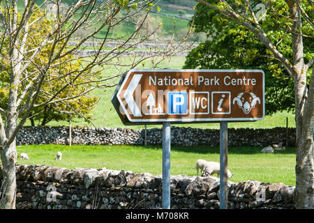 Un segnale di informazione nel Yorkshire Dales villaggio di Malham North Yorkshire Regno Unito, indirizzare i visitatori al centro del Parco Nazionale e area di servizio è Foto Stock