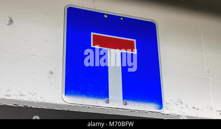 Blue dead end road sign appeso a una parete di cemento in Germania Foto Stock