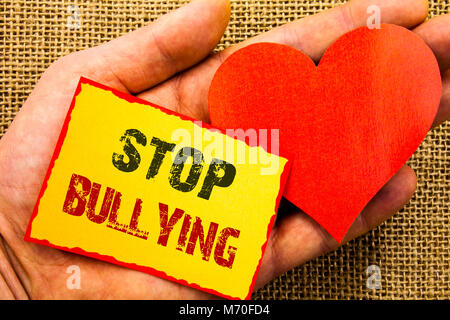 Testo della Scrittura che mostra arrestare il bullismo. Il concetto di business per il problema della consapevolezza circa la violenza abuso bullo problema scritto una nota adesiva Carta con cuore Foto Stock