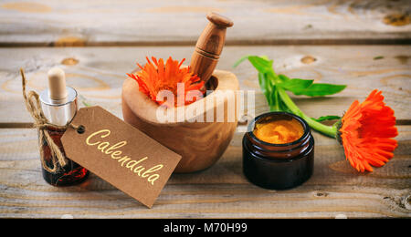 Calendula o fiorrancio aromaterapia. Olio essenziale e un unguento a base di erbe, testo calendula su un tag. Tavolo in legno sfondo Foto Stock