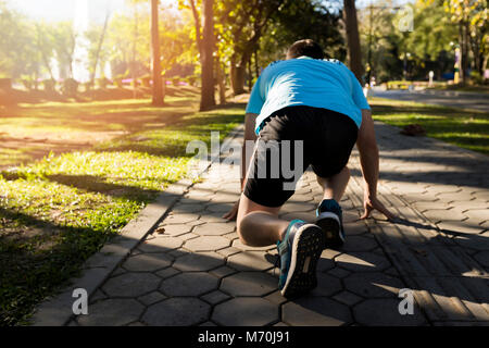 Pronti per andare! Close up tagliate ad angolo basso foto di scarpa di atleta uomo in esecuzione di avviare pongono sulla strada nel parco. Foto Stock