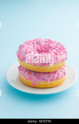 Due ciambelle rosa su sfondo blu. Foto Stock