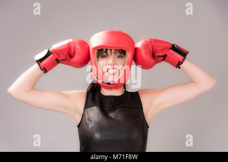 Donna boxer con un espressione facciale indossando un headguard rosso e rosso guantoni da pugilato, circa 2018 Foto Stock