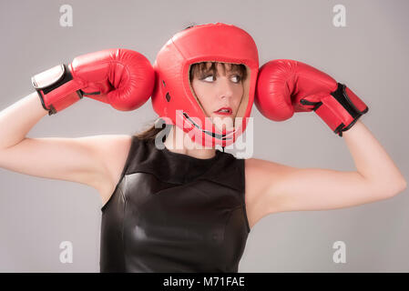 Donna boxer con un espressione facciale indossando un headguard rosso e rosso guantoni da pugilato, circa 2018 Foto Stock