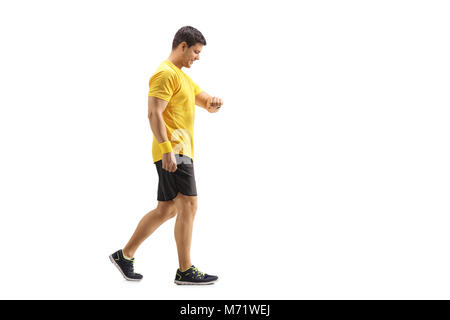 Lunghezza piena ripresa di profilo di un giovane uomo che cammina e guardando il suo orologio isolato su sfondo bianco Foto Stock