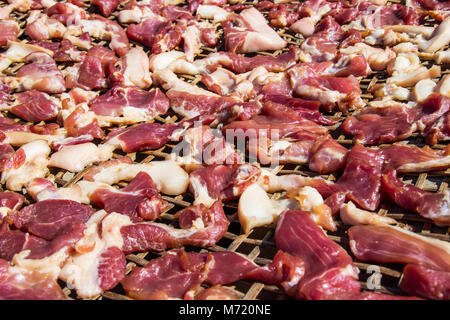 Conservazione della carne suina a secco con sole-essiccati su bamboo basket weave palat. Foto Stock