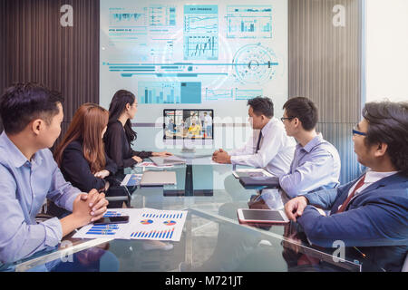 Gruppo di asian Business team di video conferenza con il loro manager tramite il display del monitor in una moderna sala conferenze, la gente di affari sale riunioni con Foto Stock
