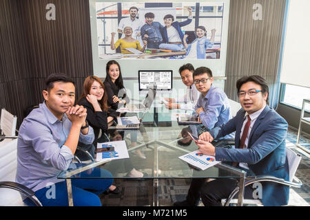 Gruppo di asian Business team avente video conferenza con un altro collega di team con i loro manager tramite tecnologia display monitor nel moderno confe Foto Stock