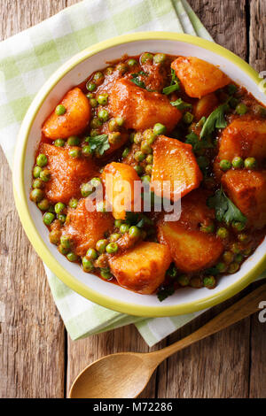 Indiano Vegetariano, Aloo Matar realizzato da patate, piselli verdi, erbe e salsa piccante closeup su una piastra. Verticale in alto vista da sopra Foto Stock