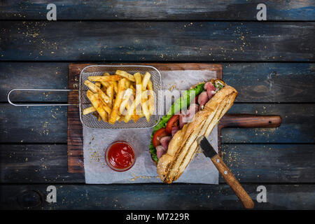 Grandi sandwich di pane con verdure e arrosto di manzo sul tagliere di legno Foto Stock