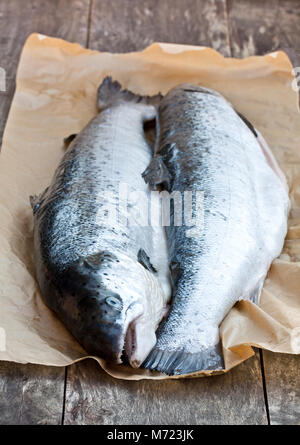 Chiudere su un intero crudo di salmoni sfondo di legno Foto Stock