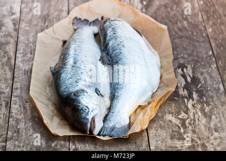 Chiudere su un intero crudo di salmoni sfondo di legno Foto Stock