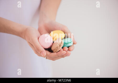 Dolce con. Macaron colorati in mani femminili. Foto Stock
