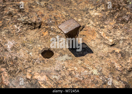 Chiodo di ferro nella roccia con vicino il foro di un chiodo estratto Foto Stock