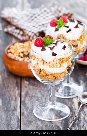 Muesli con crema e lamponi freschi in un bicchiere Foto Stock