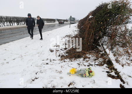 Due giovani di età compresa tra 17 e 18, passano fiori posti presso la scena sulla A61 nei pressi di Thirsk nel North Yorkshire dove due ragazzi morti e due bambini sono tra sette feriti dopo un tre auto-crash. Foto Stock