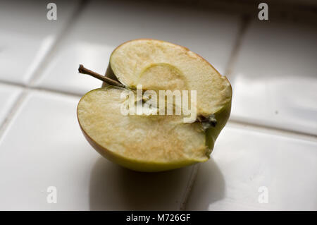 Un Apple tagliate a metà su un bianco superficie piastrellata Foto Stock