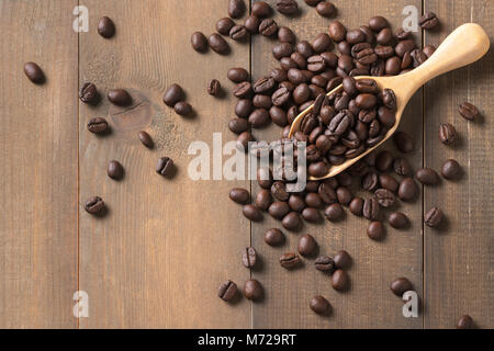 Caffè torrefatto in grani in legno e scoop su uno sfondo di legno, vista dall'alto e copiare lo spazio per testo Foto Stock
