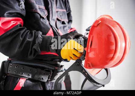 Importanza di indossare attrezzature di protezione. Sito in costruzione tema. Lavoratore con elmetto e una protezione per il viso Maschera di maglia. Foto Stock