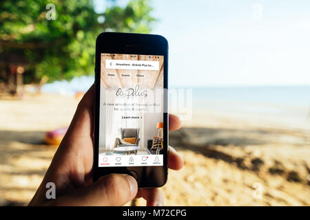 Primo piano dello schermo di iPhone con AirBNB PLUS Startscreen presso una spiaggia Foto Stock