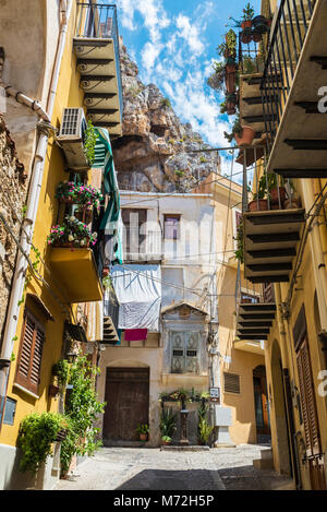 Strada stretta con balconi con capi appesi nella città vecchia del villaggio storico di Cefalù in Sicilia, Italia Foto Stock