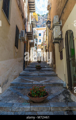 Strada stretta con passi nel centro storico del villaggio storico di Cefalù in Sicilia, Italia Foto Stock