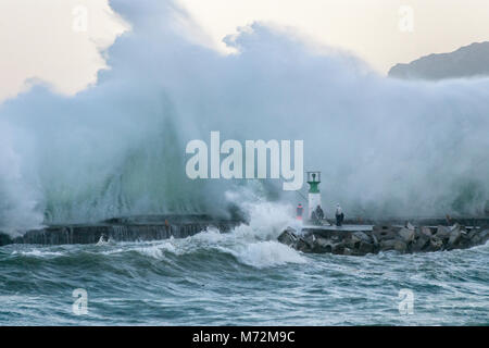 I pescatori sfidando le onde enormi che si sono visti qui di schiantarsi contro il frangiflutti di Kalk Bay Harbor in Cape Town, Sud Africa. Foto Stock