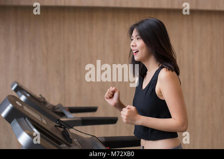 Giovane donna asiatica allenamento su tapis roulant in palestra Foto Stock