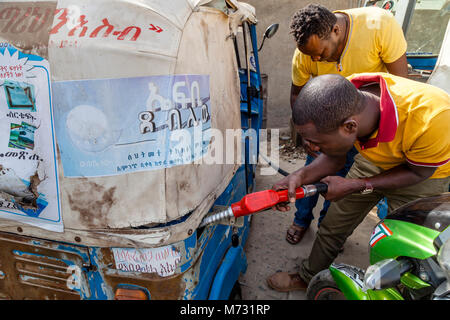 Un Bajaj (Tuk Tuk) Driver il rifornimento il Suo veicolo, Arba Minch, Gamo Gofa Zona, Etiopia Foto Stock