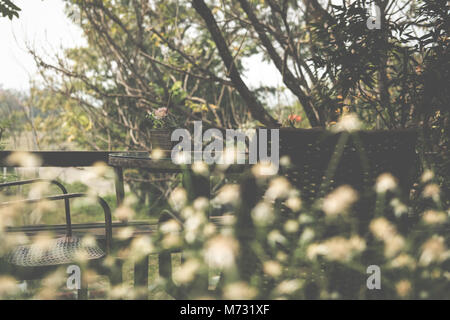 Tavolo tondo in legno sulla terrazza di casa. vimini sedie di rattan sul patio giardino vicino a casa. Stile di vita rilassante concetto. Foto Stock