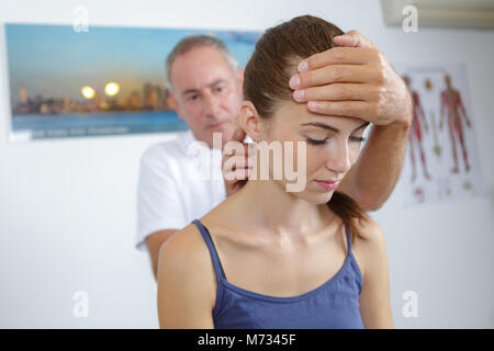 Fisioterapista maschio dando massaggio della testa al paziente di sesso femminile in clinica Foto Stock