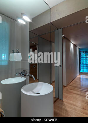 Scatti di interni di un moderno bagno in primo piano la colonna lavabo , il grande specchio e rubinetto in acciaio Foto Stock