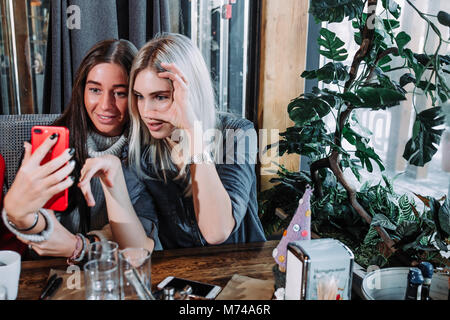 Due ragazze a pranzo in un cafe e facendo selfie Foto Stock