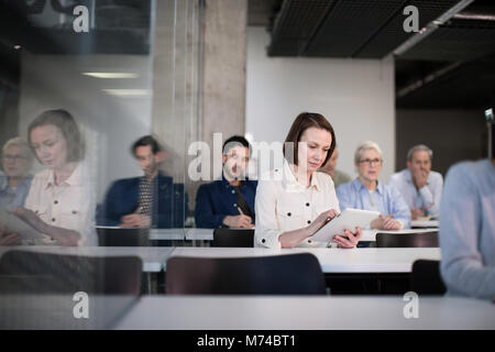 Coppia studente prendendo appunti sulla tavoletta digitale in una lezione Foto Stock