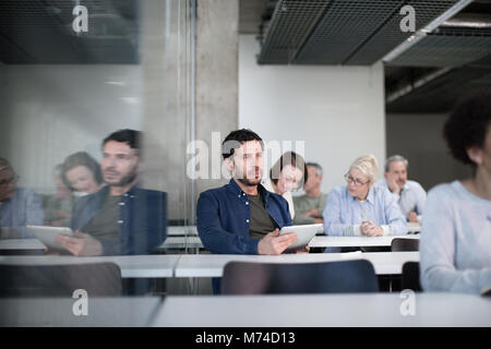 Coppia studente prendendo appunti sulla tavoletta digitale in una lezione Foto Stock