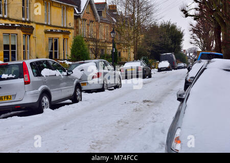 Luce neve che ricoprono le città strada residenziale con tracce di auto, Bristol, Regno Unito Foto Stock