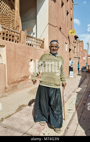 Abyaneh, Iran - 26 Aprile 2017: anziani uomo iraniano con una bacchetta passeggiate attraverso il villaggio di montagna. Foto Stock