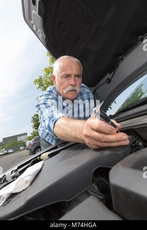 Uomo in pensione la manutenzione la sua auto a motore Foto Stock