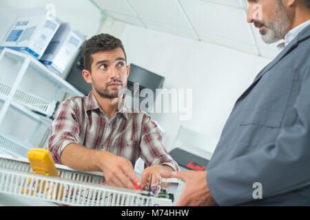 Factory manager e ingegneria apprendista discutendo il componente Foto Stock